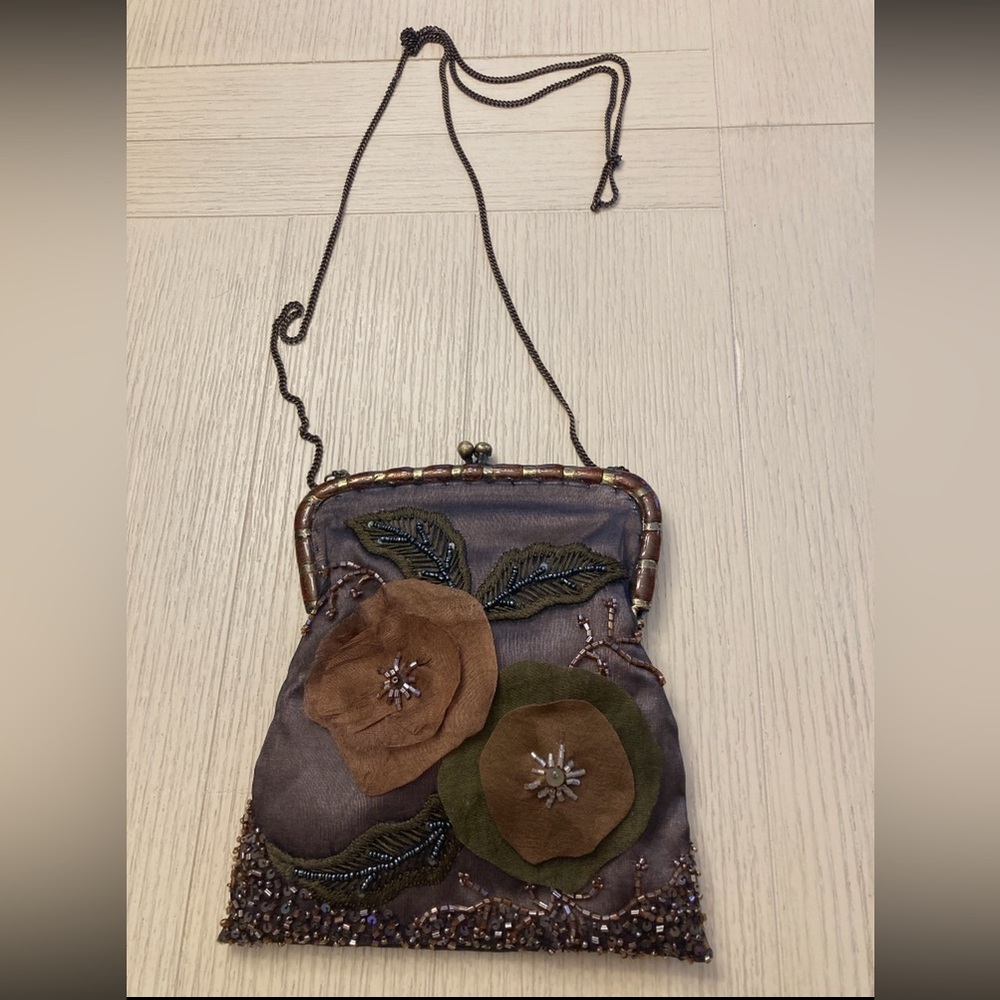 Vintage-style silk handbag with floral appliqués and a delicate chain strap.